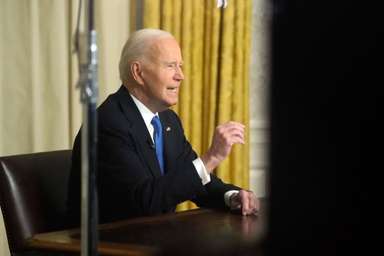 As seen through a window from the Colonnade outside the Oval Office, former President Joe Biden speaks during his farewell address at the White House in Washington, Wednesday, Jan. 15, 2025.