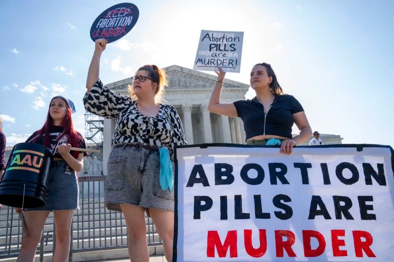 Staff with the group, Progressive Anti-Abortion Uprising, Kristin Turner, of San Francisco, left, Lauren Handy, of Washington, and Caroline Smith, of Washington, right, demonstrate against abortion pills outside of the Supreme Court, Friday, April 21, 2023, ahead of an abortion pill announcement by the court in Washington.