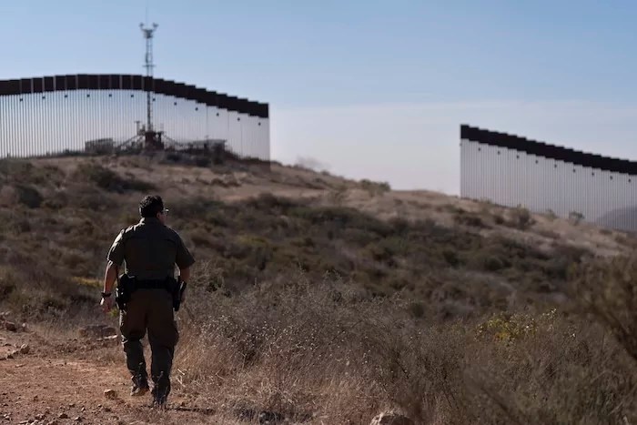 A Border Patrol agent walks toward a gap in one of two border walls separating Mexico from the United States, Thursday, Jan. 23, 2025, in San Diego.