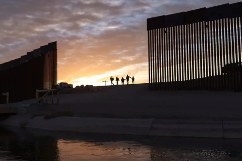 A pair of migrant families from Brazil pass through a gap in the border wall to reach the United States to seek asylum after crossing from Mexico in Yuma, Arizona, June 10, 2021.