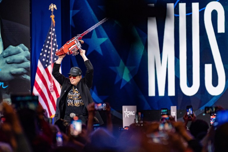 Tech billionaire Elon Musk holds a chainsaw onstage at CPAC.