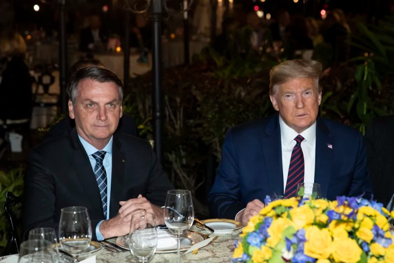 President Donald Trump, right, sits alongside Brazilian President Jair Bolsonaro during a dinner at Mar-a-Lago in Palm Beach, Florida, March 7, 2020. (AP Photo/Alex Brandon, File)