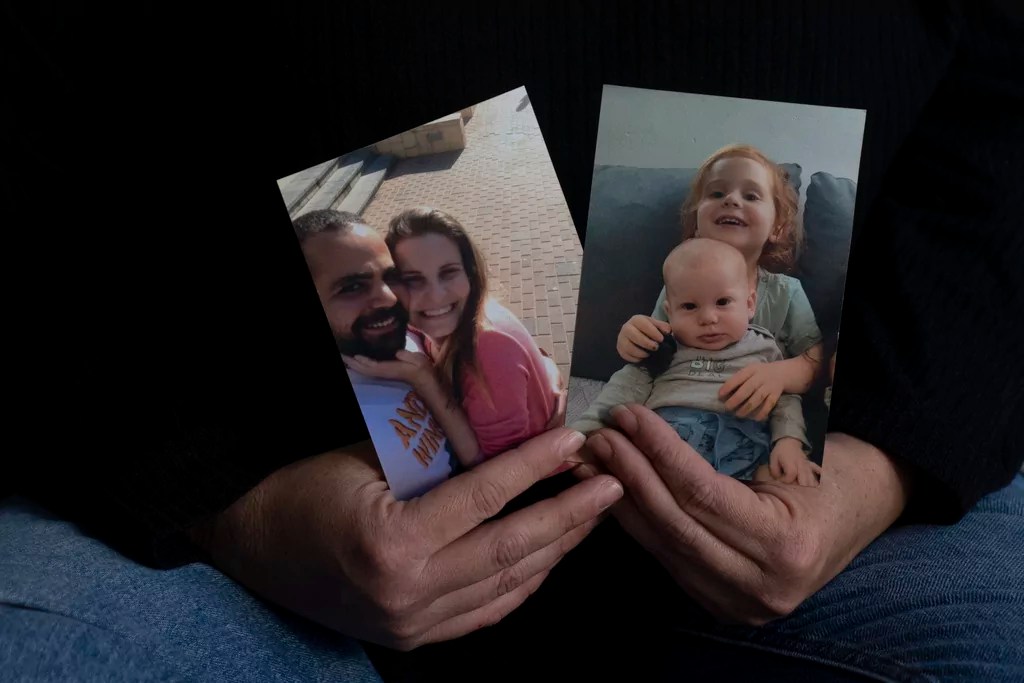 Yifat Zailer shows photos of her cousin, Shiri Bibas, center, her husband Yarden, left, and their children Ariel, top right, and Kfir, who are held hostage by Hamas in the Gaza Strip, at home in Herziliyya, Israel, Wednesday, Jan. 15, 2025. Kfir was an infant when they were captured and is now marking his second birthday. (AP Photo/Maya Alleruzzo)