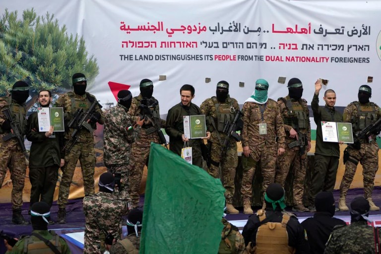 Israeli hostages, from left to right, Eliya Cohen, Omer Shem and Omer Wenkert, show Hamas issued certificates on a stage after being instructed by militants, before being handed over to the Red Cross in Nuseirat, central Gaza Strip, Saturday, Feb. 22, 2025. (AP Photo/Abdel Kareem Hana)