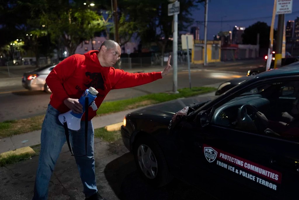 Ron Gochez, a teacher volunteering with Union del Barrio, an organization advocating for immigrant rights, waves to other volunteers as they head out to search for ICE activity in a neighborhood in Los Angeles Thursday, Feb. 27, 2025.