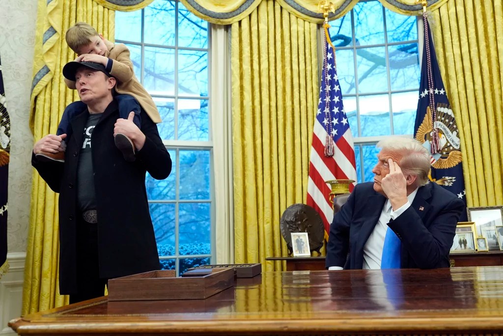 President Donald Trump listens as Elon Musk, joined by his son X Æ A-Xii, speaks in the Oval Office at the White House, Tuesday, Feb. 11, 2025, in Washington. (AP Photo/Alex Brandon)
