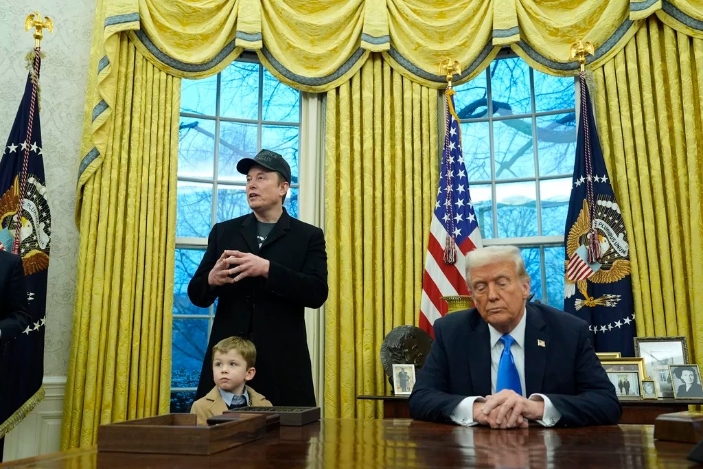 President Donald Trump listens as Elon Musk, joined by his son X Æ A-Xii, speaks in the Oval Office at the White House, Tuesday, Feb. 11, 2025, in Washington. (AP Photo/Alex Brandon)
