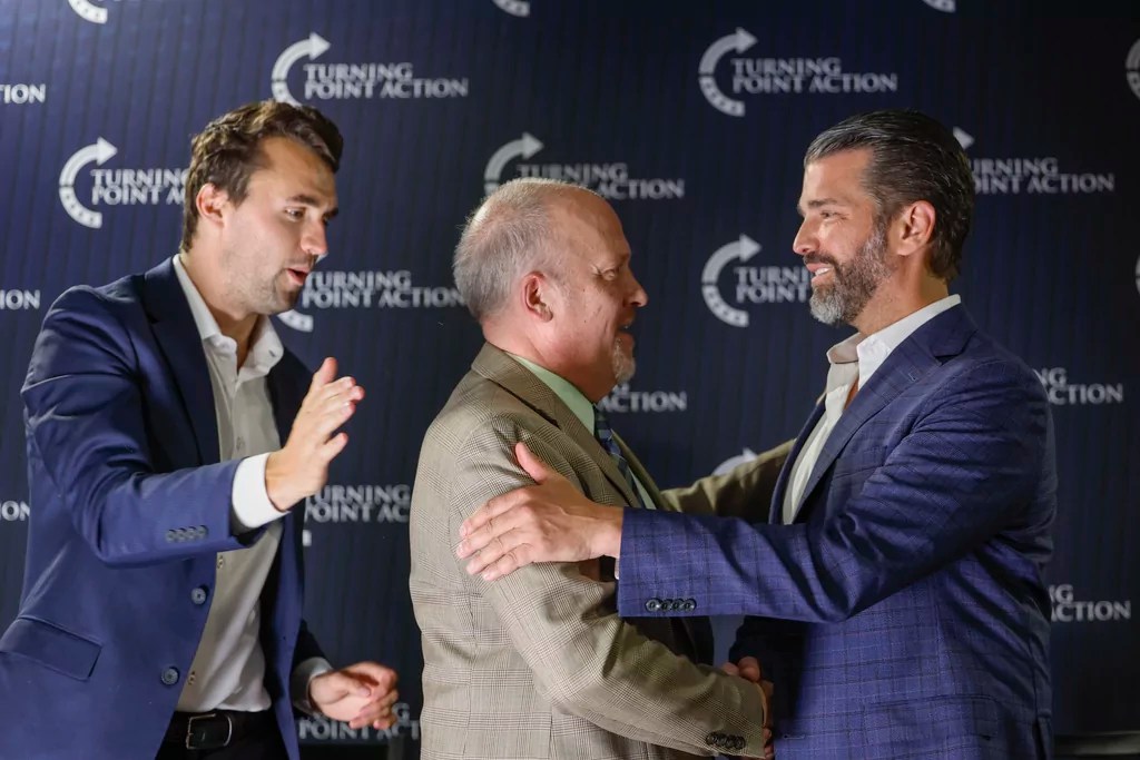 Former Wisconsin Attorney General and state Supreme Court candidate Brad Schimel, middle, greets Donald Trump Jr., as Charlie Kirk looks on during a town hall Monday, March 17, 2025, in Oconomowoc, Wis.