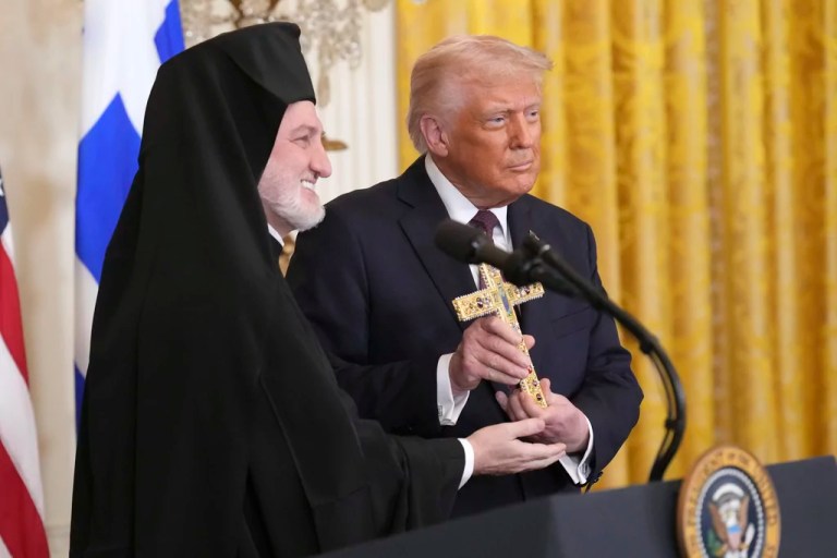 Archbishop Elpidophoros of the Greek Orthodox Archdiocese of America, left, presents a cross to President Donald Trump, right, at a reception celebrating Greek Independence Day in the East Room of the White House, Monday, March 24, 2025, in Washington.