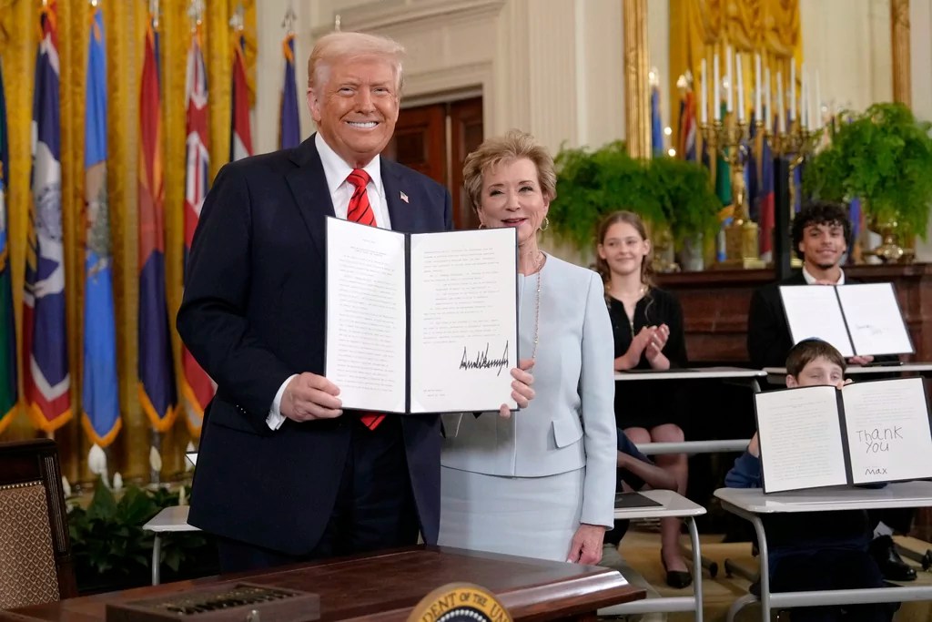 President Donald Trump holds up a signed executive order alongside Secretary of Education Linda McMahon in the East Room of the White House in Washington, Thursday, March 20, 2025. (AP Photo/Ben Curtis)