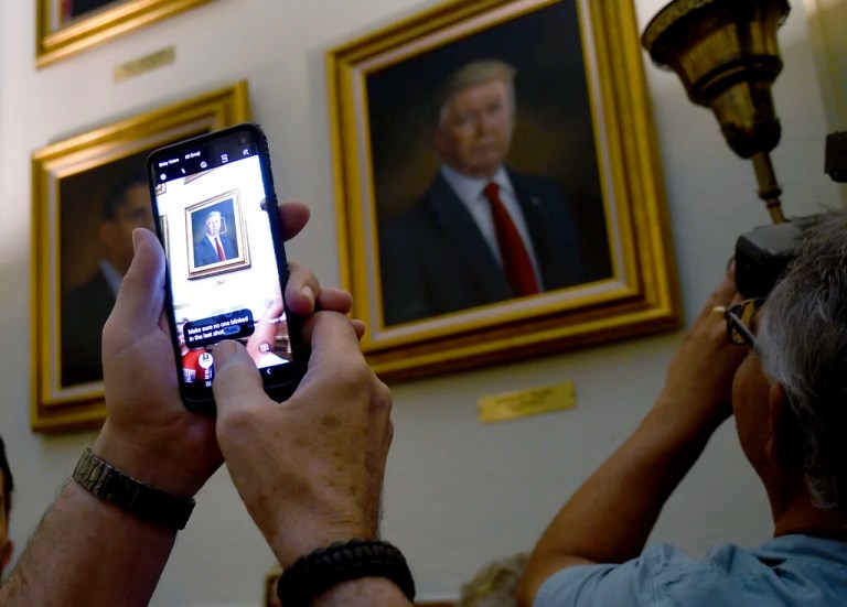 People take photos of President Donald Trump's portrait hanging in the Colorado Capitol after an unveiling ceremony Thursday, Aug. 1, 2019, in Denver. Colorado Republicans raised more than $10,000 through a GoFundMe account to commission the portrait, which was painted by Sarah Boardman, an artist who also produced the Capitol's portrait of President Barack Obama.