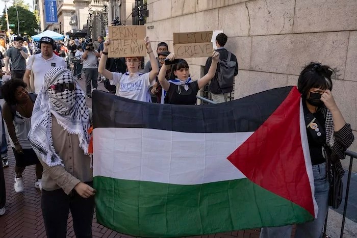 Freshman Columbia and Barnard University students Lila and Shoshana raise signs while pro-Palestinian supporters protest outside Columbia University, Tuesday, Sep. 3, 2024, in New York.