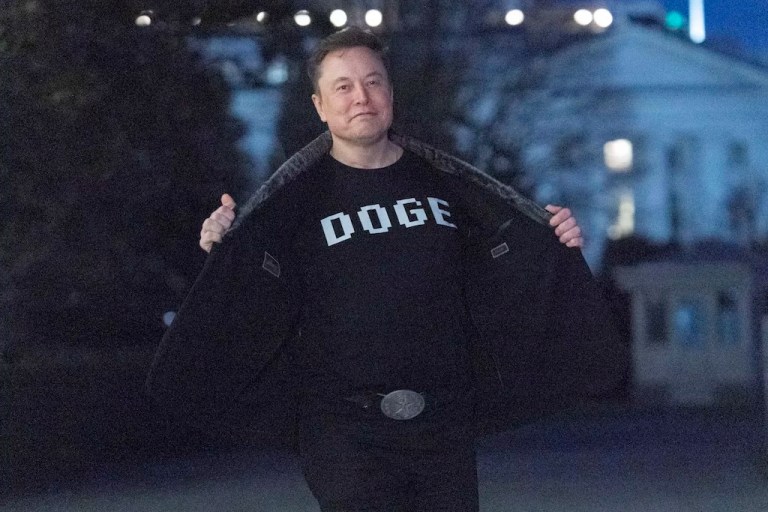 Elon Musk flashes his t-shirt that reads 
