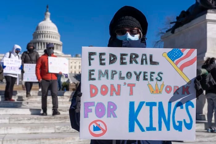 A federal employee, who asked not to use their name for fears over losing their job, protests with a sign saying 