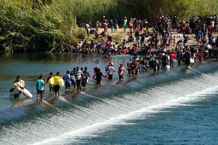 Haitian migrants use a dam to cross to and from the United States from Mexico, Friday, Sept. 17, 2021, in Del Rio, Texas. Thousands of Haitian migrants have assembled under and around a bridge in Del Rio presenting the Biden administration with a fresh and immediate challenge as it tries to manage large numbers of asylum-seekers who have been reaching U.S. soil. (AP Photo/Eric Gay)