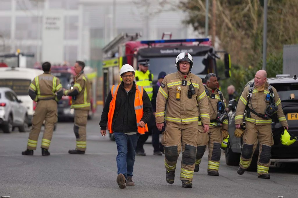 Firefighters wait at the area around the North Hyde electrical substation, which caught fire Thursday night and lead to a closure of Heathrow Airport in London, Friday, March 21, 2025.