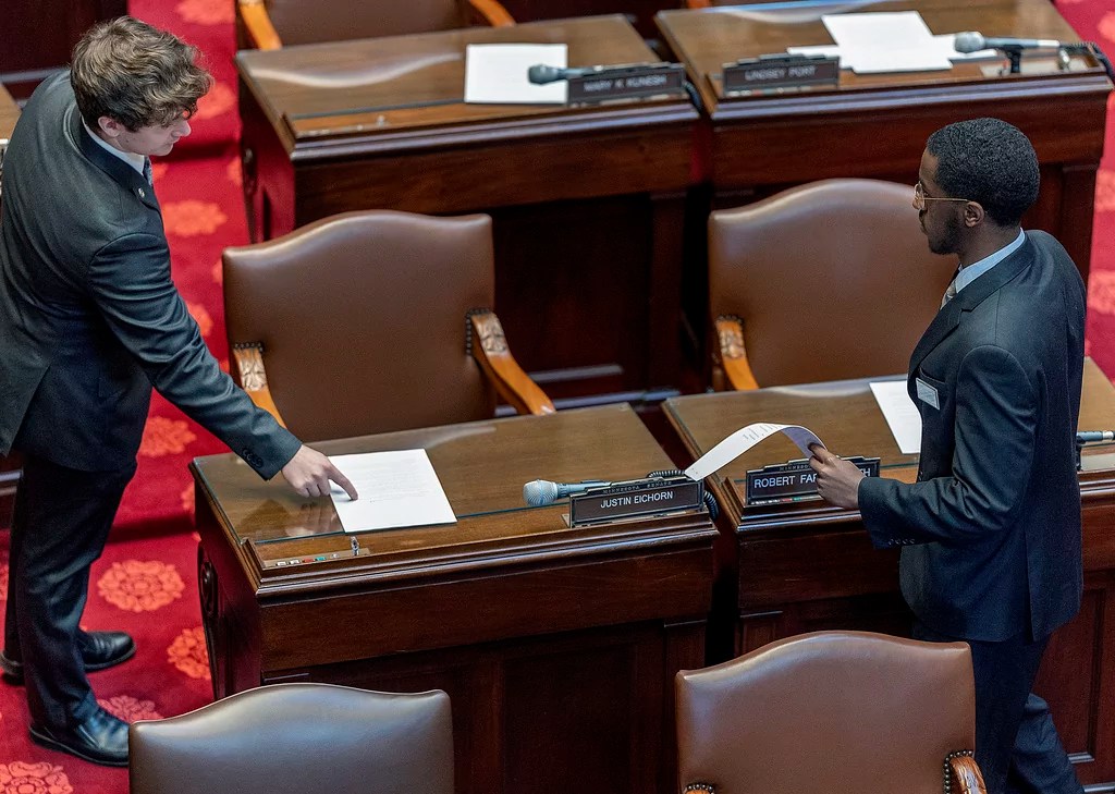 Staff place the agenda on the desk of GOP Minnesota state Sen. Justin Eichorn before his name was removed before the morning's session and Eichorn's resignation at the Minnesota State Capitol in St. Paul, Minn., on Thursday, March 20, 2025.
