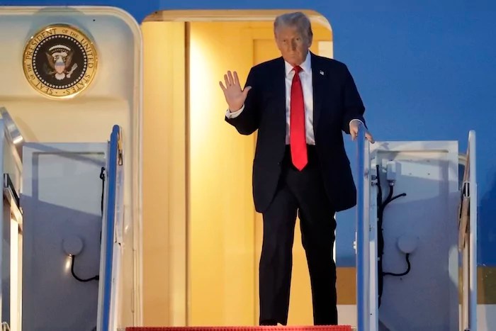 President Donald Trump waves as he walks down the stairs of Air Force One upon his arrival at Joint Base Andrews, Md., Sunday, March 30, 2025. (AP Photo/Luis M. Alvarez)