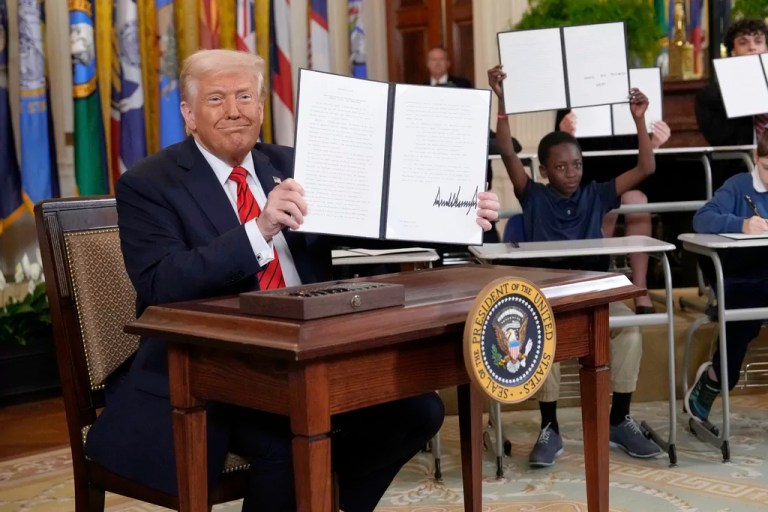 President Donald Trump holds up a signed executive order in the East Room of the White House in Washington, Thursday, March 20, 2025.
