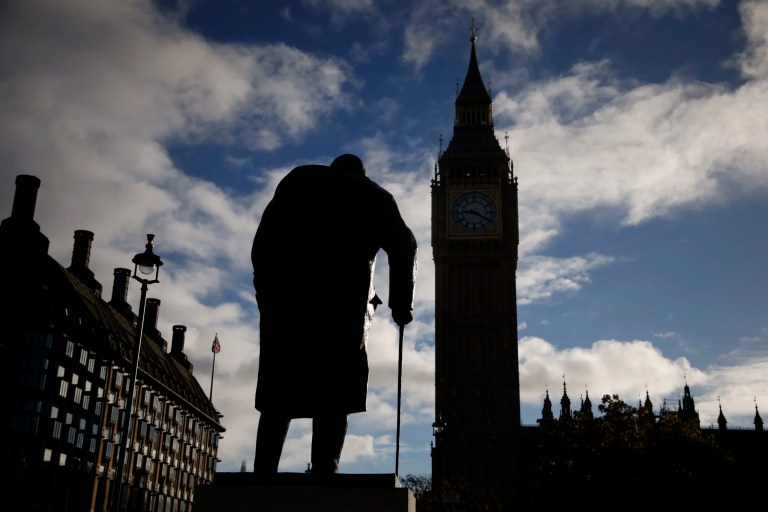 The statue of wartime prime minister Winston Churchill is seen next to the Big Ben tower of Houses of Parliament, right, at sunrise in London, Monday, Oct. 24, 2022.