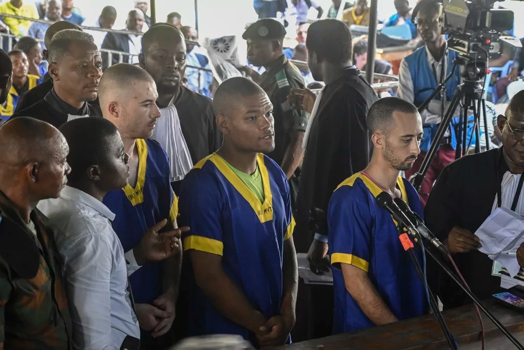 Tyler Thompson Jr., Marcel Malanga and Benjamin Reuben Zalman-Polun, all American citizens, face the court in Kinshasa, Congo, with 52 other defendants, June 7, 2024, accused of a role in the attempted coup in Congo led by little-known opposition figure Christian Malanga in which six people were killed.
