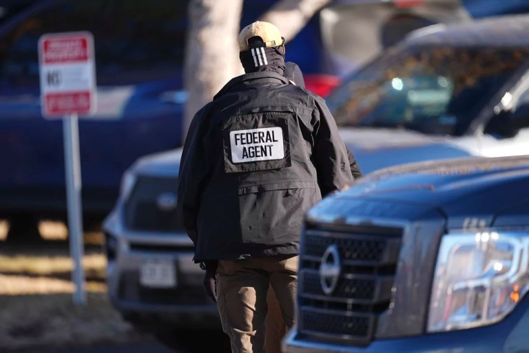 Law official guards entrance to an apartment complex during a raid Wednesday, Feb. 5, 2025, in east Denver.