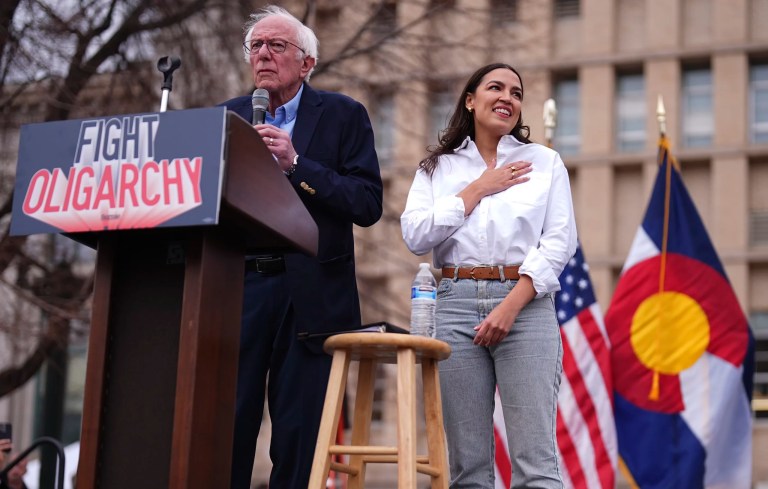 Sen. Bernie Sanders, (I-VT), left, speaks as Rep. Alexandria Ocasio-Cortez (D-NY) responds to calls of support during a stop of their 