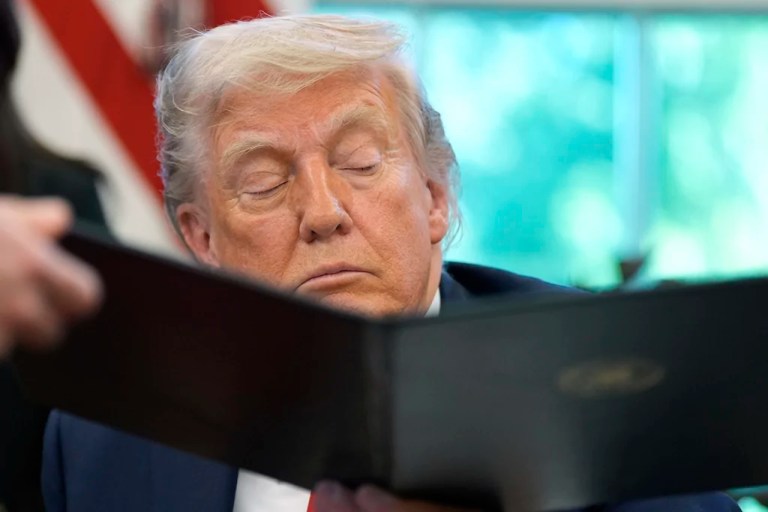 President Donald Trump is handed an executive order to sign by White House staff secretary Will Scharf in the Oval Office of the White House