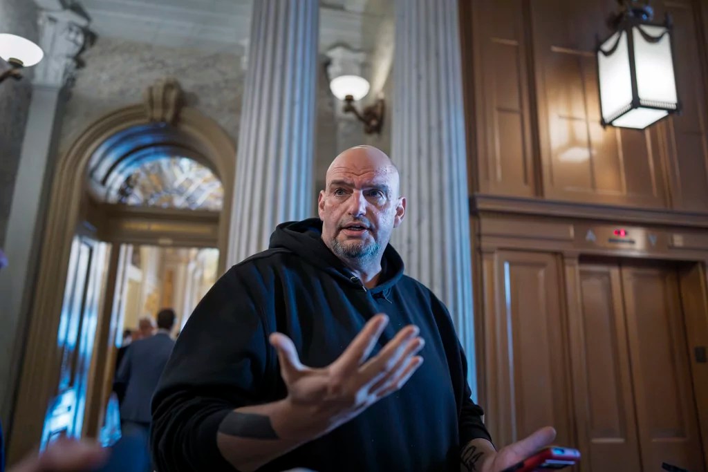Sen. John Fetterman, D-Pa., talks to reporters outside the chamber during a vote, at the Capitol in Washington, Thursday, March 13, 2025.