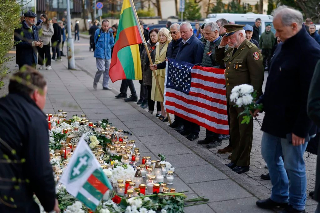People with U.S. national flag come to pay their last respect to the three soldiers found dead on Monday at a training range in Pabrade, near the U.S. Embassy in Vilnius, Lithuania, Tuesday, April 1, 2025.