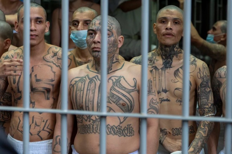 Prisoners with MS-13 gang tattoos look out of their cell as Homeland Security Secretary Kristi Noem tours the Terrorist Confinement Center in Tecoluca, El Salvador, Wednesday, March 26, 2025.