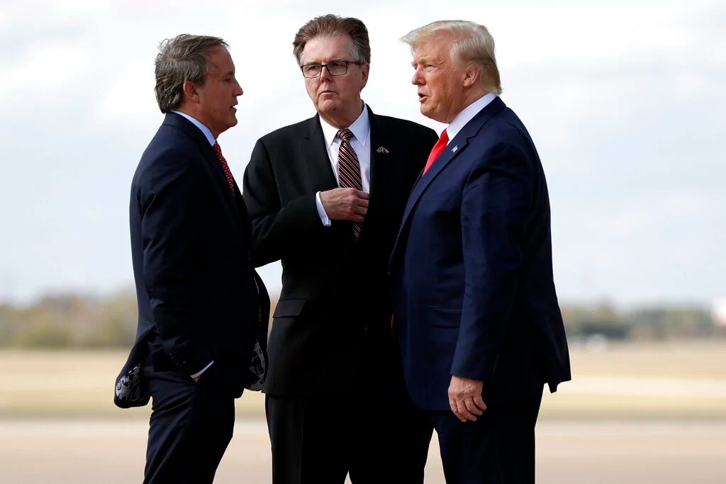 President Donald Trump talks Texas Lt. Gov. Dan Patrick, center, and Attorney General Ken Paxton, at Austin-Bergstrom International Airport for a visit to an Apple manufacturing plant, Wednesday, Nov. 20, 2019, in Austin.