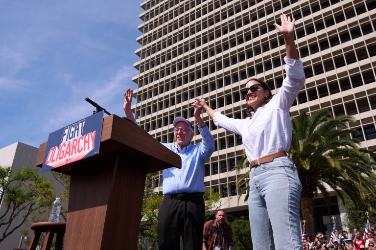Sen. Bernie Sanders (I-VT), right, and Rep. Alexandria Ocasio-Cortez (D-NY) acknowledge the cheering crowd during a 