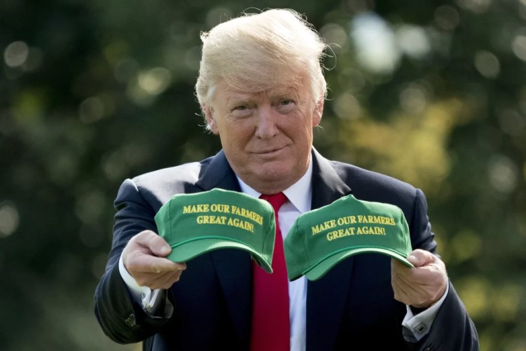President Donald Trump holds up hats that read 