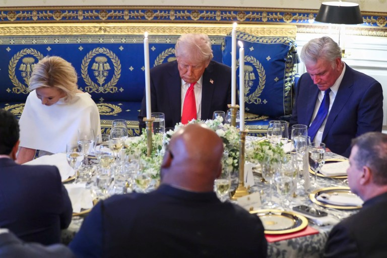 President Donald Trump bows his head during a prayer at an Easter prayer service and dinner in the Blue Room of the White House in Washington, Wednesday, April 16, 2025, with Pastor Paula White, left, and Rev. Franklin Graham, right.