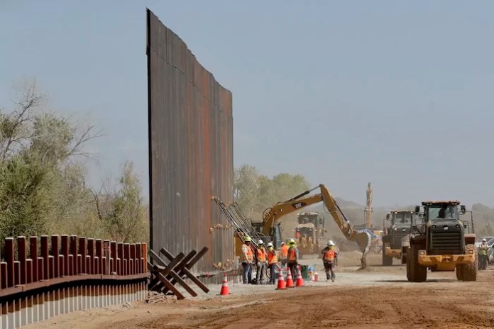 Government contractors erect a section of the Pentagon-funded border wall along the Colorado River.