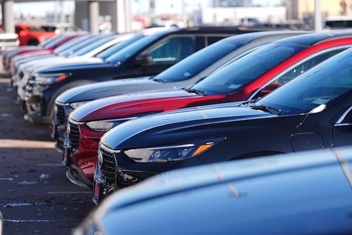 A long line of unsold 2024 Escape and Edge utility vehicles sit on display at a Ford dealership