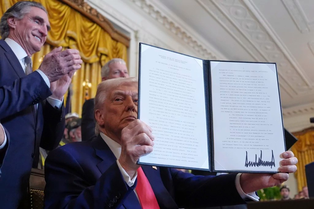 President Donald Trump holds a signed an executive order during an event in the East Room of the White House, Tuesday, April 8, 2025, in Washington, as Interior Secretary Doug Burgum watches.