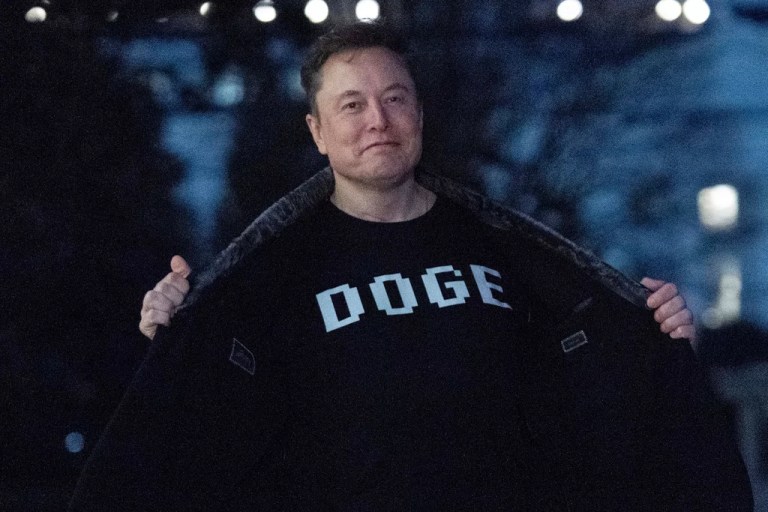 Elon Musk flashes his t-shirt that reads 