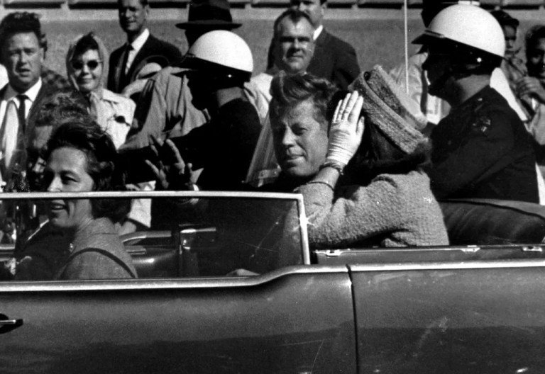 President John F. Kennedy waves from his car in a motorcade approximately one minute before he was shot, Nov. 22, 1963, in Dallas. Riding with President Kennedy are first lady Jacqueline Kennedy, right, Nellie Connally, second from left, and her husband, Texas Gov. John Connally, far left.