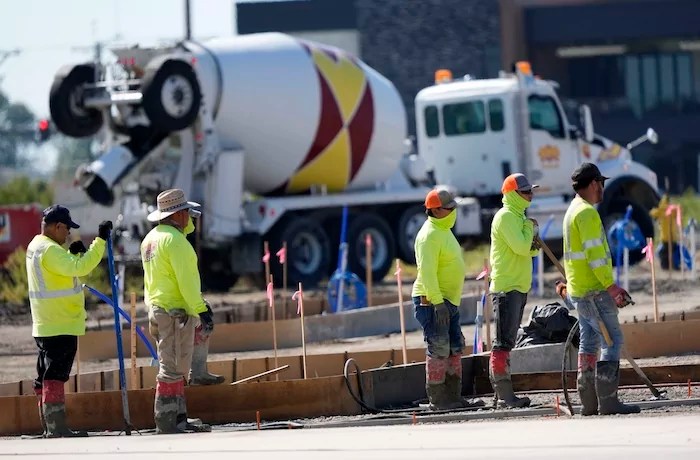 Construction crew members wait to pour concrete in a parking lot on Sept. 4, 2024, in Waukee, Iowa.