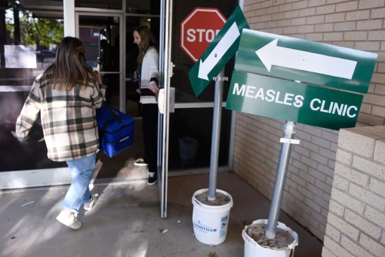 Health department staff members enter the Andrews County Health Department measles clinic carrying doses of the measles, mumps and rubella vaccine, Tuesday, April 8, 2025, in Andrews, Texas.