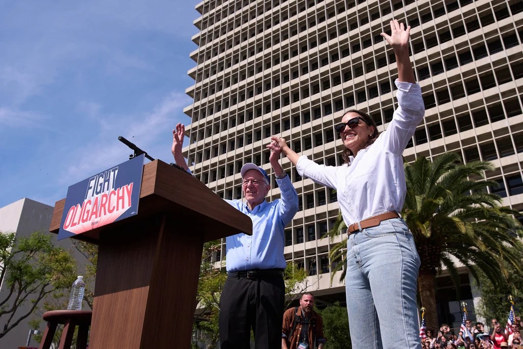 Sen. Bernie Sanders, I-Vt., right, and Rep. Alexandria Ocasio-Cortez, D-N.Y., acknowledge the cheering crowd during a "Fighting Oligarchy" event in Los Angeles, Saturday, April 12, 2025.