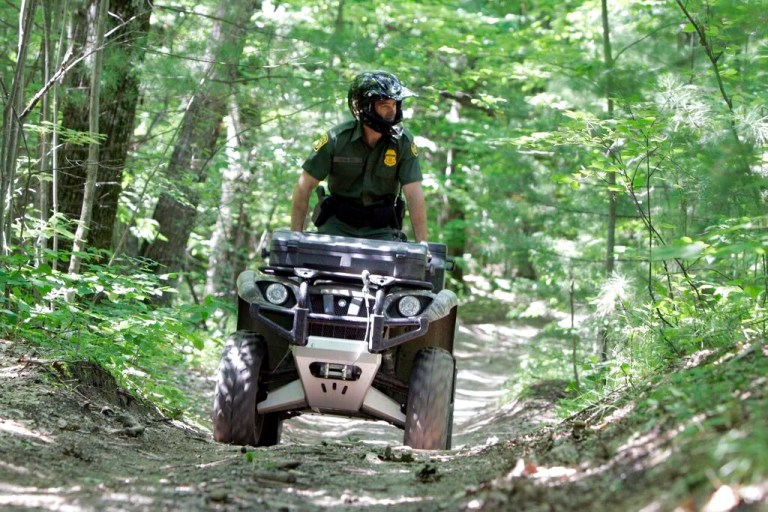 **ADVANCE FOR MONDAY JULY 21**Senior Border Patrol Agent Matthew Hayes rides an all-terrain vehicle through the woods in Swanton, Vt., Wednesday, June 25, 2008. On the northeastern arm of Lake Champlain, it's hard to tell where the U.S.-Canadian border is. There's a small buoy boaters use, but nothing else. This is when the smugglers come _ sometimes in rented boats, to a waiting getaway car on shore, sometimes walking across the border on railroad tracks, or through dense northern Vermont woods. A beefed-up law enforcement presence along the border is making a difference this year. The U.S. Border Patrol is seeing fewer organized smuggling efforts. (AP Photo/Toby Talbot)