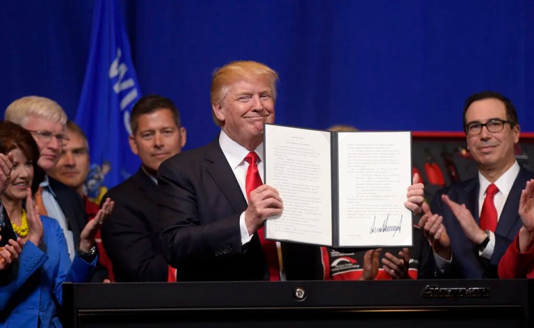 President Donald Trump holds up the 