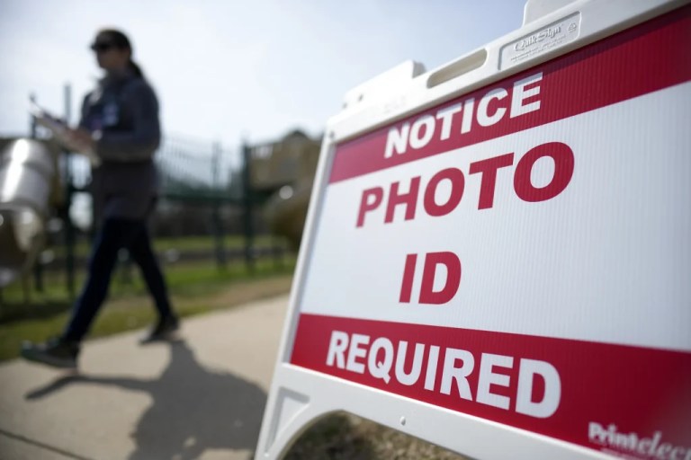 A Super Tuesday voter walks past a sign requiring a photo ID at a polling location