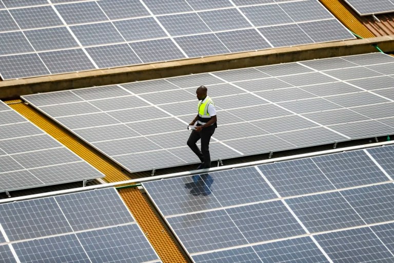 Mark Munyua, CP solar's technician, examines solar panels on a roof.