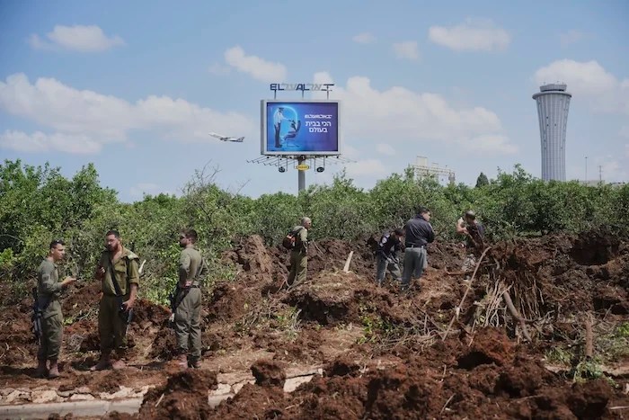Israeli security forces inspect the site where the Israeli military said a projectile fired by Yemen's Houthi rebels landed in the area of Ben Gurion International Airport near Tel Aviv, Israel, on Sunday, May 4, 2025.