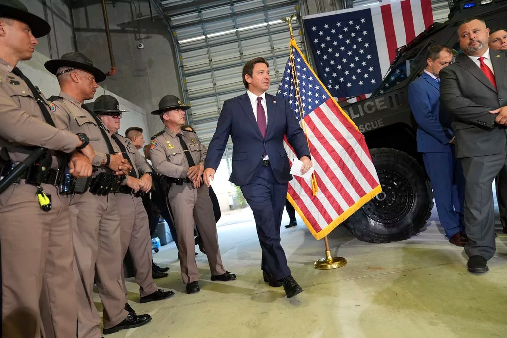 Officers of the Florida Highway Patrol, left, look on as Gov. Ron DeSantis arrives for a press conference about a recent immigration enforcement operation, at the South Florida office of U.S. Immigration and Customs Enforcement and Enforcement and Removal Operations, Thursday, May 1, 2025, in Miramar, Fla.