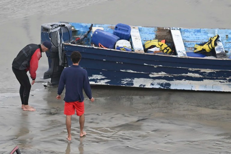 Del Mar lifeguards looks over a capsized boat on the beach Monday, May 5, 2025, in at Torrey Pines State beach in San Diego, Calif. 